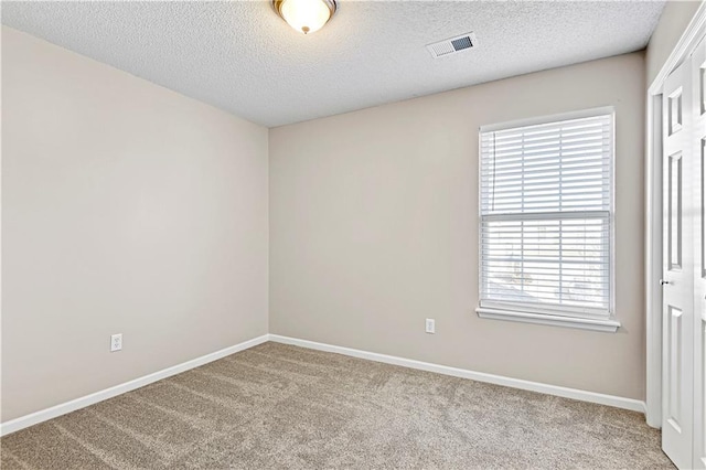 carpeted empty room with a textured ceiling, visible vents, and baseboards