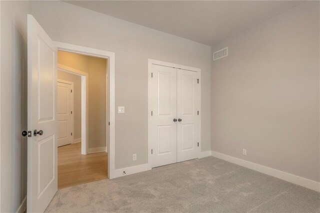 unfurnished bedroom featuring light carpet and a closet