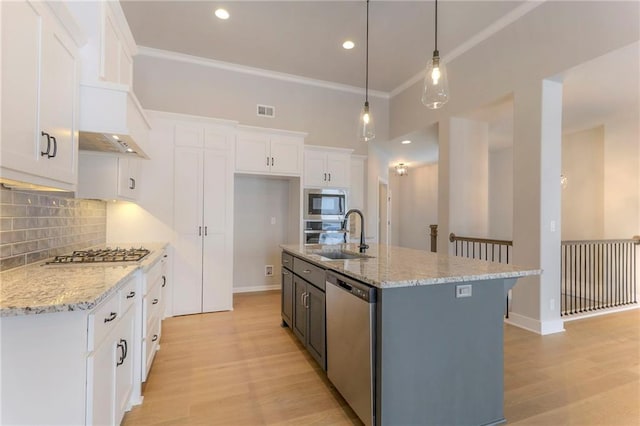 kitchen featuring appliances with stainless steel finishes, pendant lighting, white cabinetry, sink, and a center island with sink