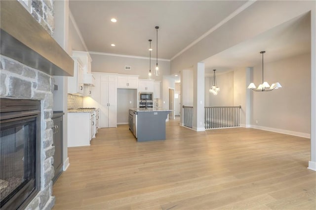 kitchen with white cabinetry, an inviting chandelier, a center island with sink, and pendant lighting