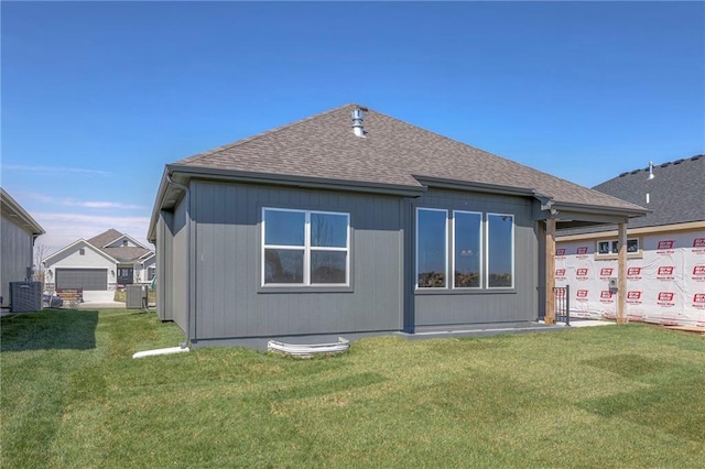 back of house featuring central AC unit and a lawn