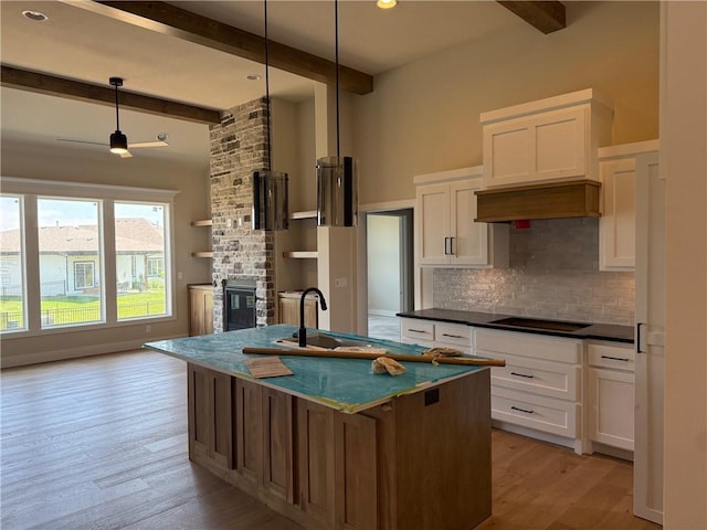 17351 S Kaw St, Olathe, KS 66062 - kitchen with decorative backsplash, beam ceiling, a large fireplace, black electric cooktop, and dark countertops