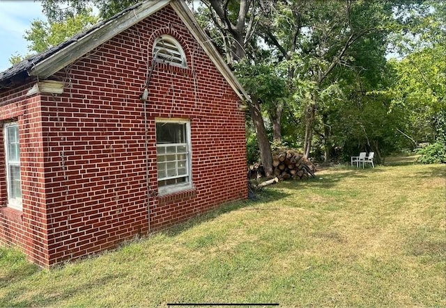 view of side of property featuring brick siding and a yard