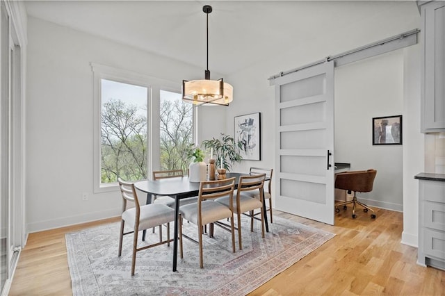 dining room with a barn door and light hardwood / wood-style floors