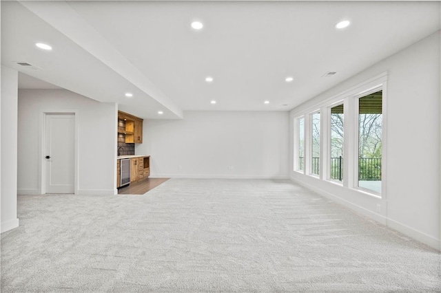 unfurnished living room with indoor bar, light colored carpet, and wine cooler