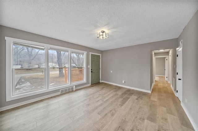 spare room with a textured ceiling and light wood-type flooring