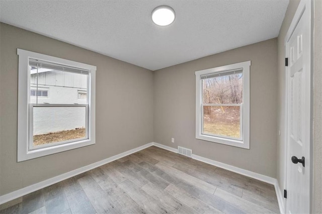 unfurnished room featuring light hardwood / wood-style flooring and a textured ceiling