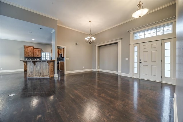 foyer entrance with an inviting chandelier, ornamental molding, and dark hardwood / wood-style floors