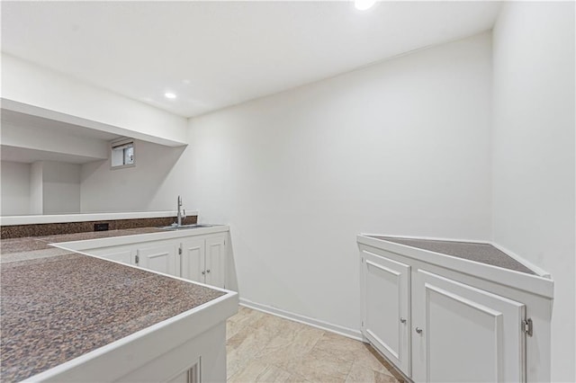 kitchen featuring dark countertops, white cabinetry, a sink, and recessed lighting