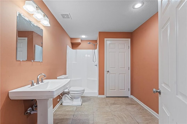 bathroom featuring toilet, baseboards, visible vents, and a shower