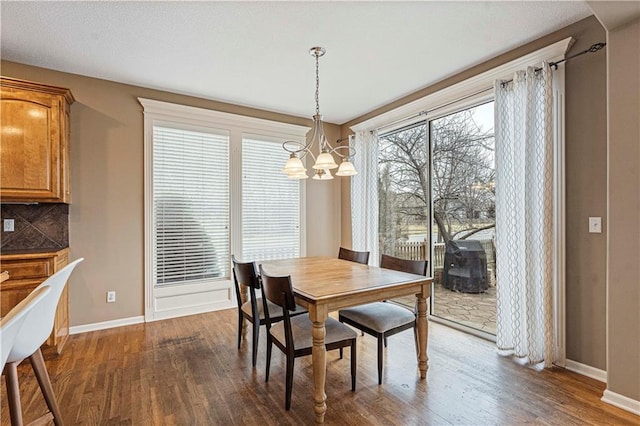 dining room featuring an inviting chandelier, baseboards, and dark wood finished floors