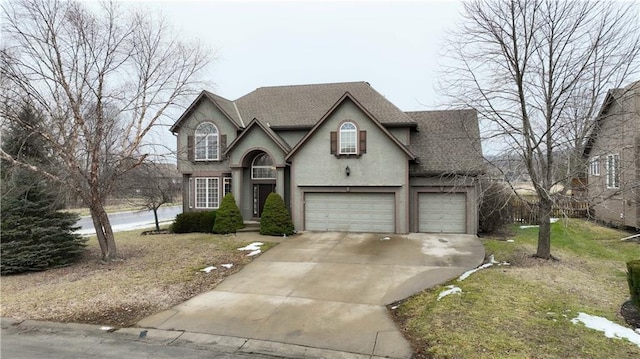 tudor-style house with concrete driveway, a shingled roof, an attached garage, and stucco siding