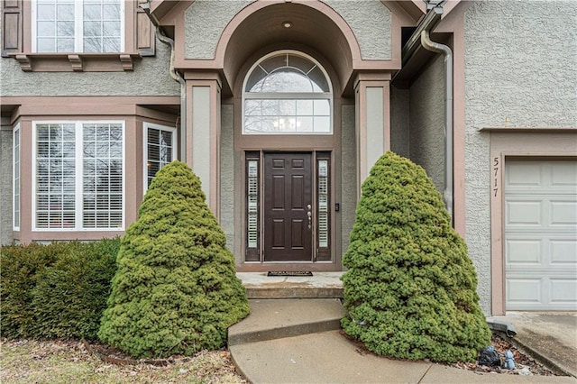 property entrance featuring a garage and stucco siding