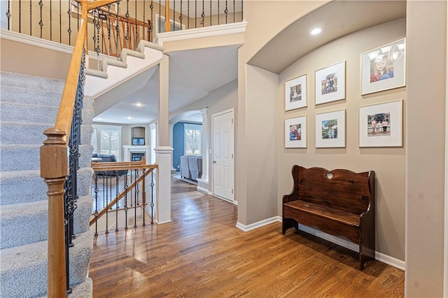 hallway featuring baseboards, a high ceiling, arched walkways, and wood finished floors