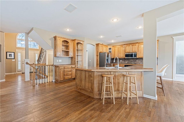 kitchen featuring a peninsula, light countertops, appliances with stainless steel finishes, a wealth of natural light, and open shelves