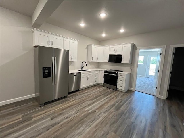 kitchen with stainless steel appliances, sink, dark wood-type flooring, and white cabinets