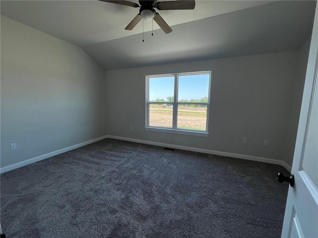 spare room featuring lofted ceiling, dark carpet, a ceiling fan, and baseboards