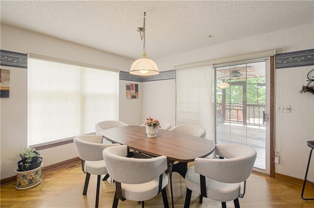 dining space featuring light hardwood / wood-style floors and a textured ceiling