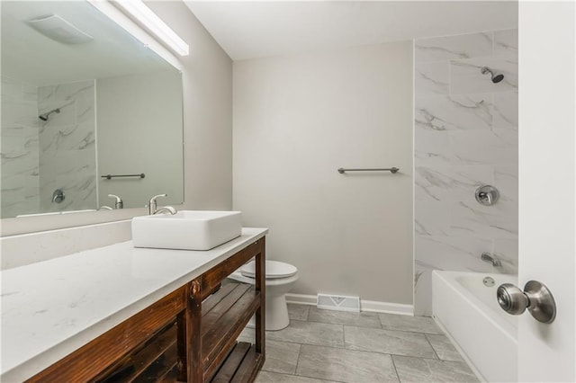 full bathroom with tiled shower / bath, vanity, and toilet