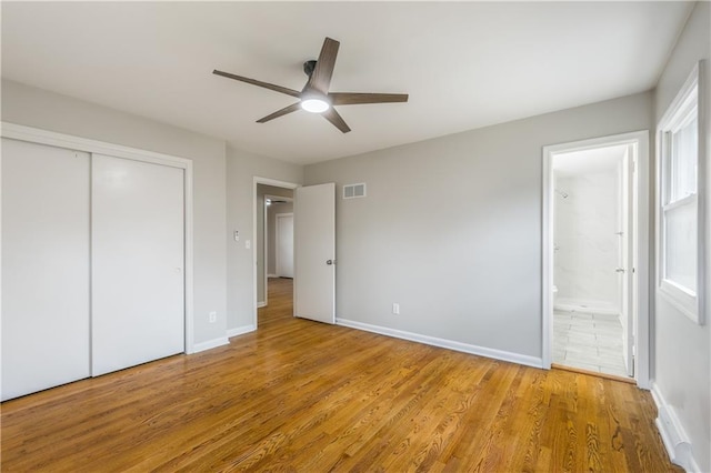 unfurnished bedroom featuring ceiling fan, connected bathroom, a closet, and light wood-type flooring