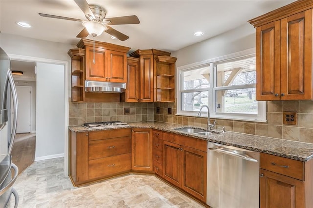 kitchen with sink, dark stone countertops, appliances with stainless steel finishes, ceiling fan, and backsplash