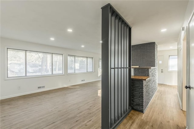 hallway with baseboards, light wood finished floors, visible vents, and recessed lighting