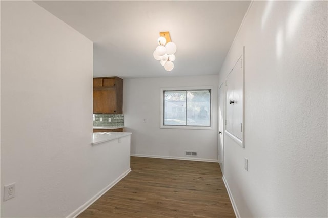 spare room with dark wood-style floors, visible vents, and baseboards