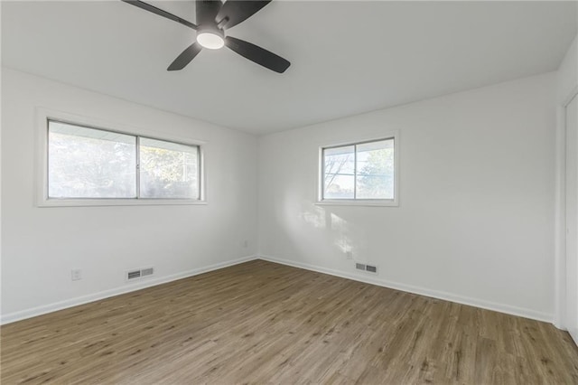 empty room featuring baseboards, visible vents, ceiling fan, and wood finished floors