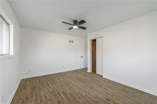 spare room featuring a ceiling fan, baseboards, visible vents, and wood finished floors