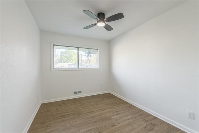 spare room with a ceiling fan, wood finished floors, visible vents, and baseboards