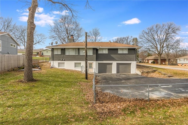 exterior space with a chimney, a lawn, fence, a garage, and driveway