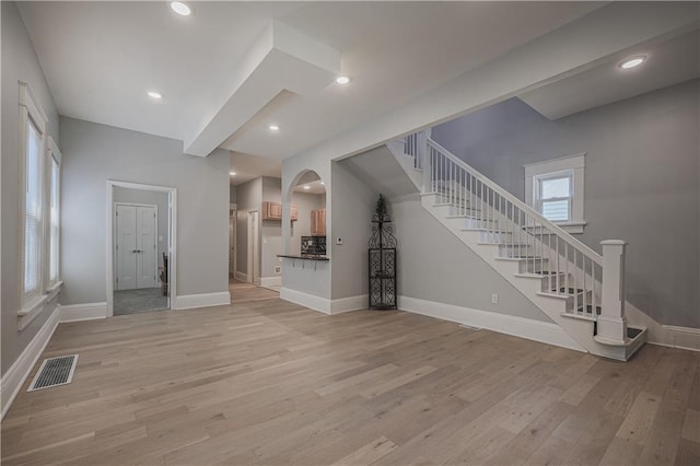 unfurnished living room with light hardwood / wood-style floors and beamed ceiling