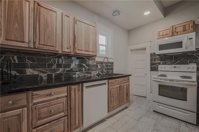 kitchen featuring sink, backsplash, white appliances, and dark stone counters