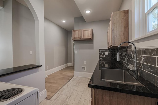 kitchen with sink, backsplash, white range with electric stovetop, and light hardwood / wood-style flooring