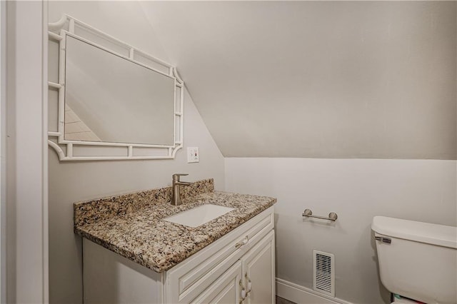 bathroom with vanity, lofted ceiling, and toilet