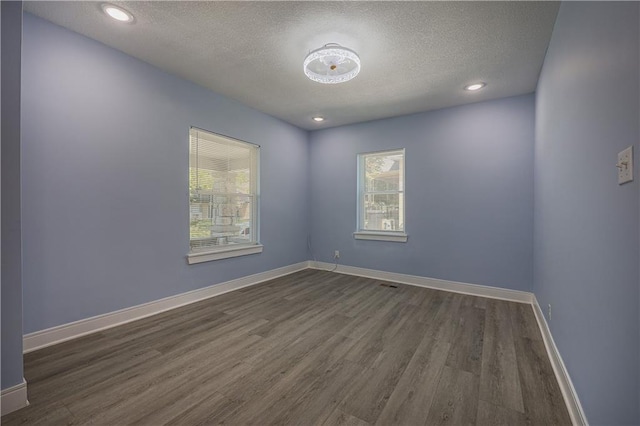 unfurnished room featuring dark wood-type flooring and a textured ceiling