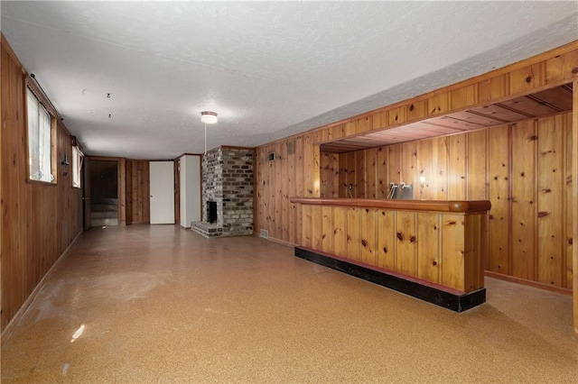 bar featuring a textured ceiling, a fireplace, and wood walls