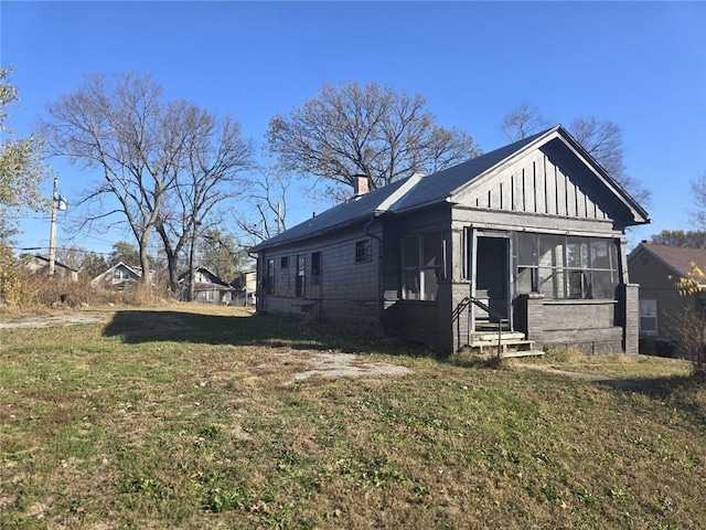 view of home's exterior with a sunroom and a yard