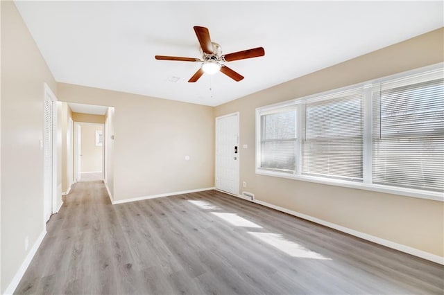 empty room with ceiling fan and light hardwood / wood-style flooring