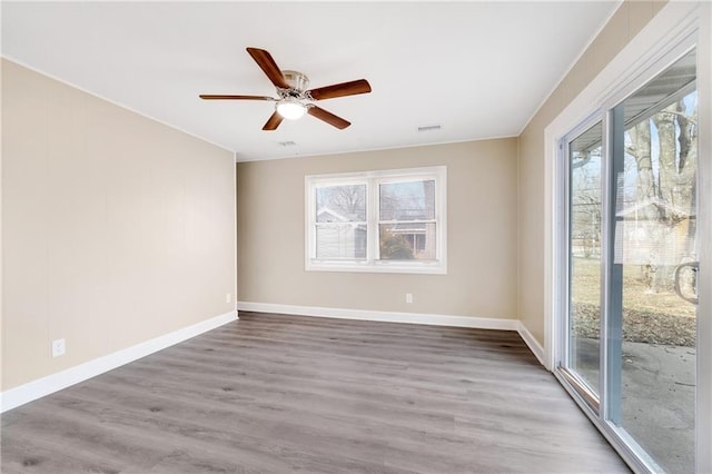 empty room with ceiling fan, a wealth of natural light, and wood-type flooring