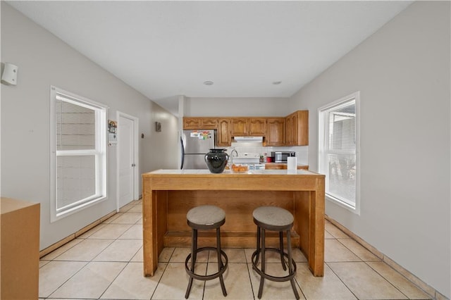 kitchen featuring appliances with stainless steel finishes, light tile patterned floors, and a kitchen bar