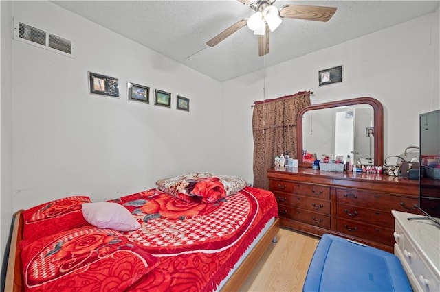 bedroom featuring ceiling fan, a textured ceiling, and light wood-type flooring