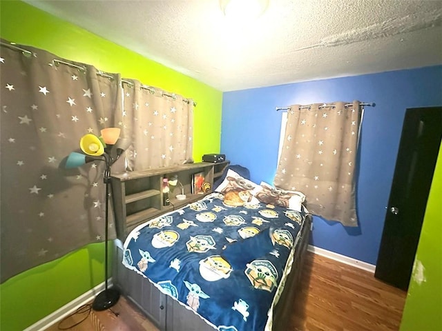 bedroom featuring a textured ceiling, baseboards, and dark wood-type flooring