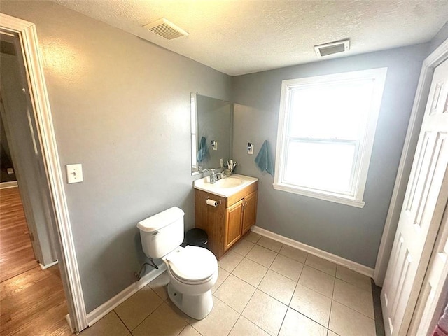 bathroom with toilet, vanity, visible vents, and baseboards