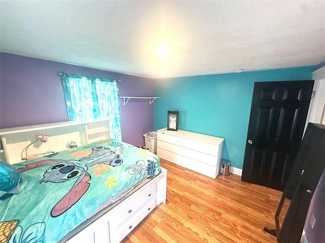 bedroom featuring light wood finished floors and baseboards