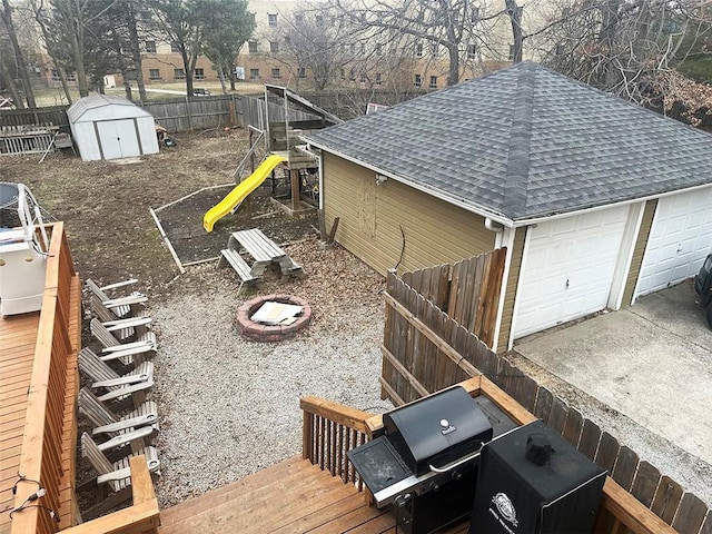 view of yard featuring a storage shed, an outdoor fire pit, an outbuilding, fence, and a playground