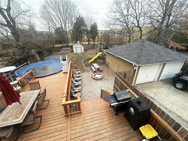 wooden terrace with an outbuilding, a playground, an outdoor fire pit, fence, and a shed