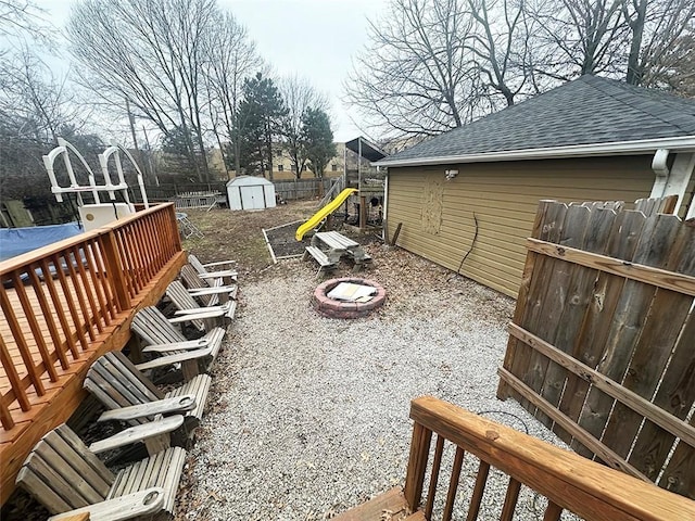 view of yard featuring an outbuilding, fence, a fire pit, and a shed