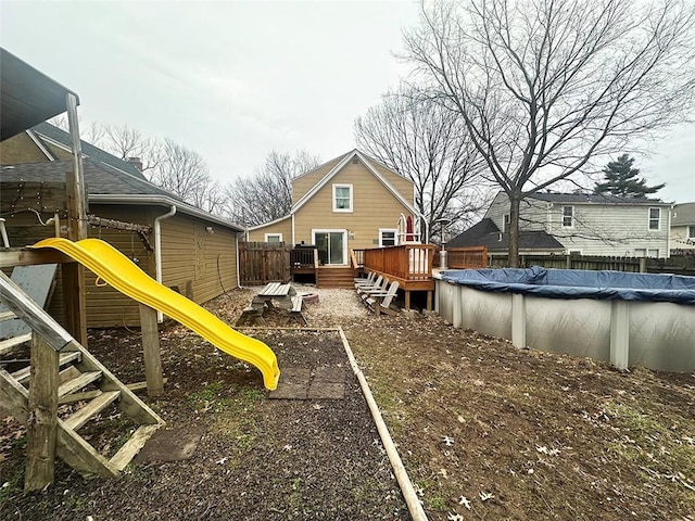 view of yard with a covered pool, a deck, and a playground