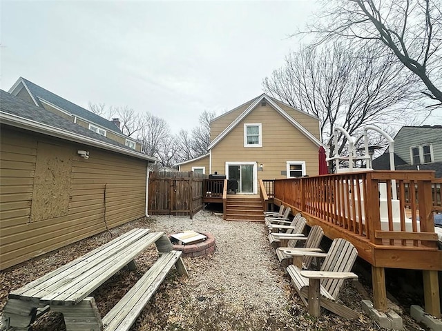 rear view of property featuring a deck, an outdoor fire pit, and fence